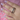 Sterling silver ring shaped like an earthworm on hand with lilac fingernails and pink background